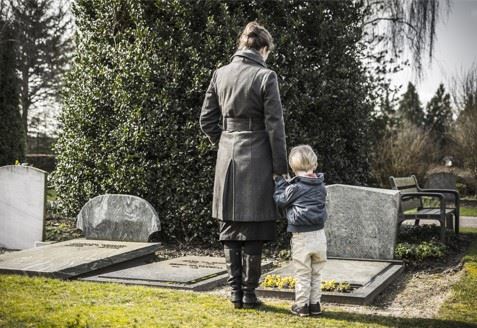 mother and son standing at a graveside mourning loss of loved one